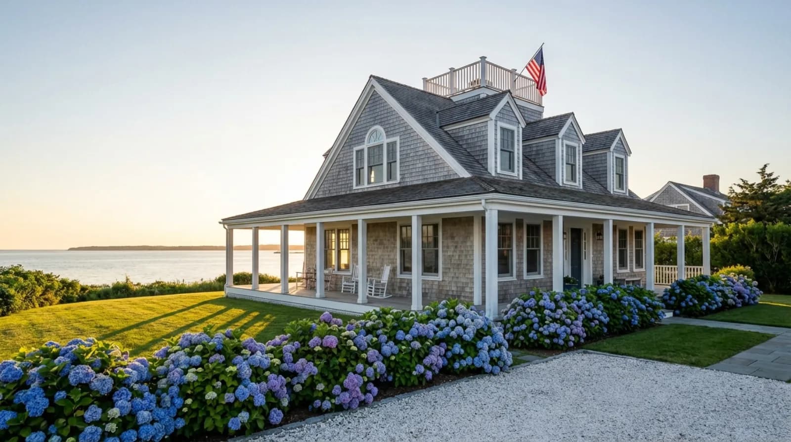 Cape Cod shingle-style second home with hydrangeas and ocean views at golden hour