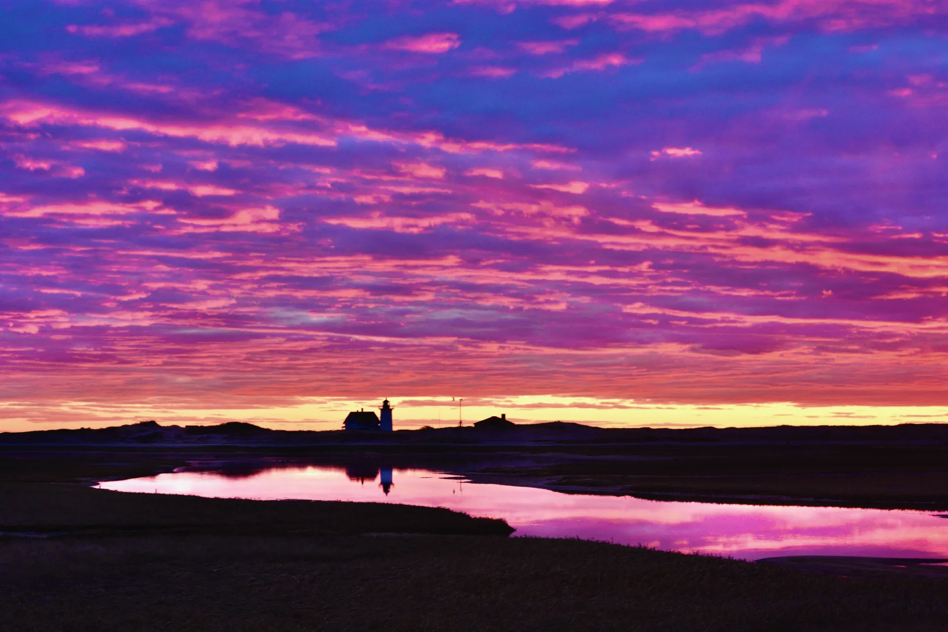 Dramatic purple and magenta sunrise over Race Point lighthouse in Provincetown